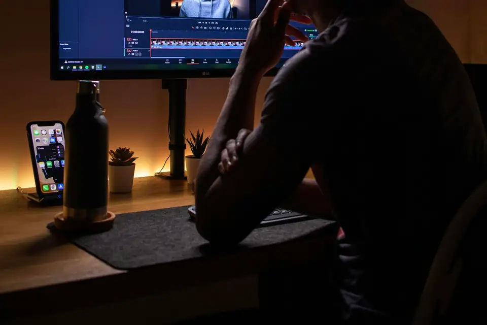 Editor with headphones reviewing a cut in a dark edit suite